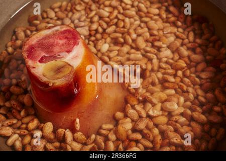 Dried pinto beans with a ham hock in a pot Stock Photo