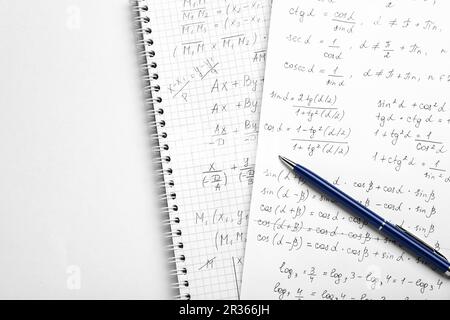 Sheets of paper with different mathematical formulas and pen on white table, top view. Space for text Stock Photo