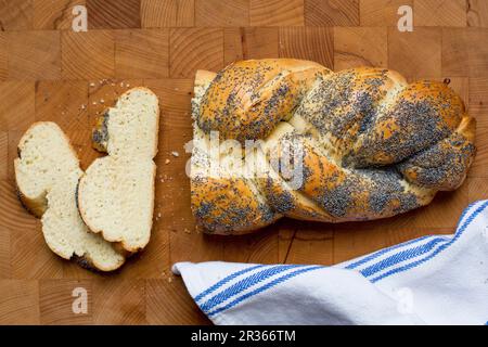 A poppyseed plait, sliced, on a wooden surface Stock Photo