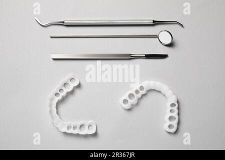 Bite correction. Mouth guards and dentist tools on light grey background, flat lay Stock Photo