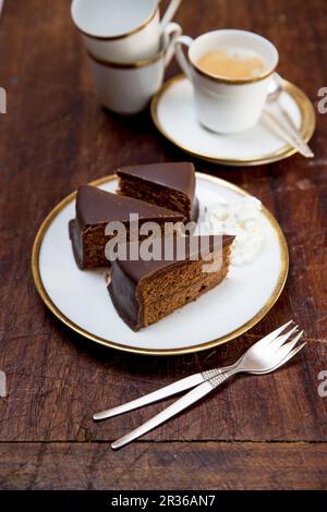 Sachertorte (rich Austrian chocolate cake) with whipped cream and a cup of coffee Stock Photo