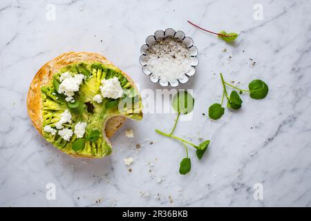 A bagel with avocado, ricotta, watercress, salt and pepper Stock Photo