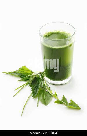 A green smoothie in a glass on a white surface Stock Photo