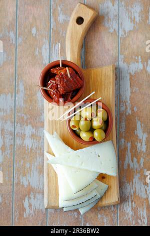 Triangles of Spanish cheese, stuffed olives and dried tomatoes (Spain) Stock Photo
