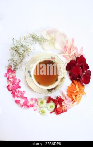 A cup of tea surrounded by various flowers (seen from above) Stock Photo