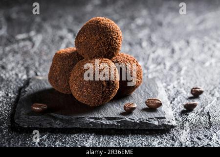 Truffle pralines with coffee beans on a black stone Stock Photo