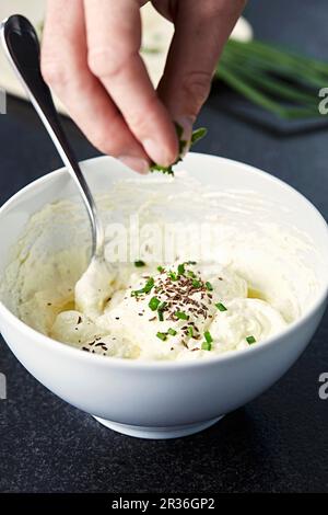 Quark and flaxseed oil spread being sprinkled with herbs Stock Photo