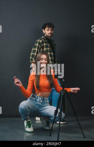 Smartphone device helping adults to record funny video for social media, creating content. Brother and sister bloggers dancing at mobile phone camera Stock Photo
