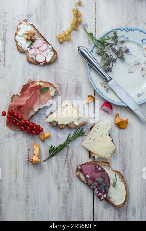 Various slices of bread with different toppings on a white wooden surface Stock Photo