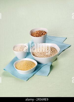 Rice, spelt, barley and couscous in white bowls Stock Photo