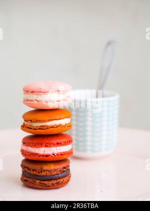 A pile of macarons in front of a cup of coffee Stock Photo
