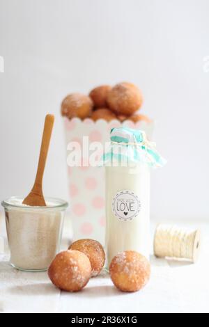 Milk in a decorative glass bottle and quark doughballs with cinnamon sugar Stock Photo