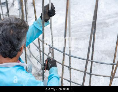 Workers use pliers to tie wire to rebar  for concrete structure Stock Photo