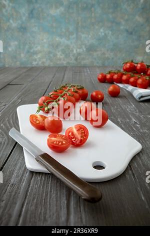 Cherry tomatoes on a chopping board, whole and halved Stock Photo