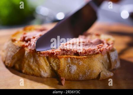 Liver pâté being spread on a slice of baguette Stock Photo