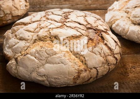 Large loaves of bread baked in a wood-fired oven on a wooden surface Stock Photo