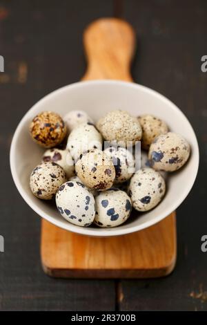Quail eggs in a bowl on a chopping board Stock Photo
