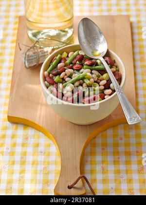 Bean salad in a bowl on a wooden board Stock Photo