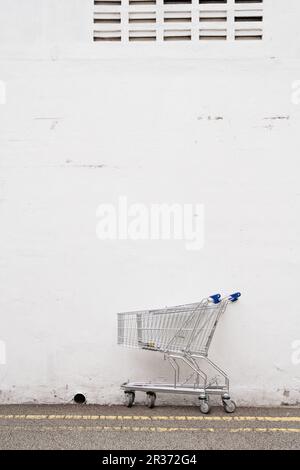 Shopping cart trolley on outdoor street with white wall Stock Photo