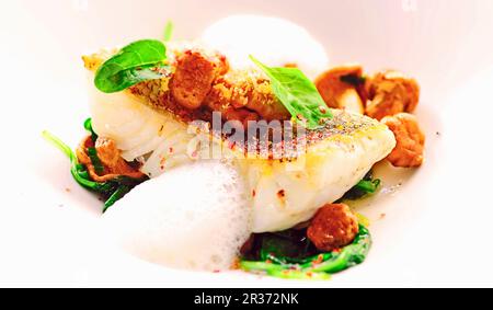 Pike-perch on a bed of spinach and chanterelles Stock Photo