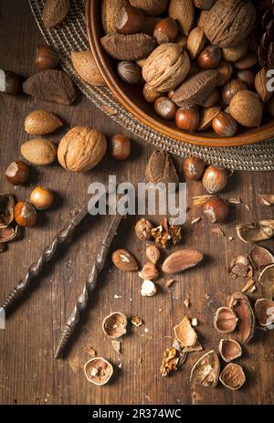 Festive bowl of mixed whole nuts in shells in a wooden bowl on a gold placemat Stock Photo