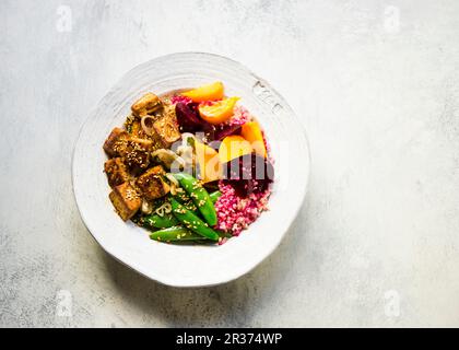 Pickled golden and red beets tossed with quinoa, topped with grilled tofu and sugar snap peas Stock Photo