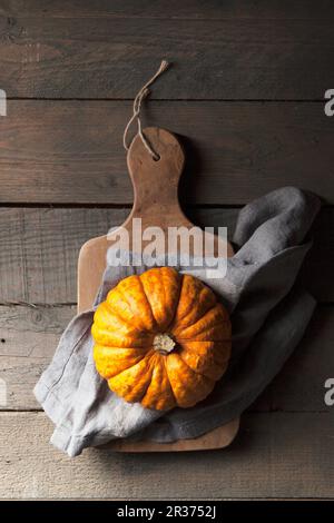 A munchkin pumpkin on a rustic wooden background with a grey linen napkin Stock Photo
