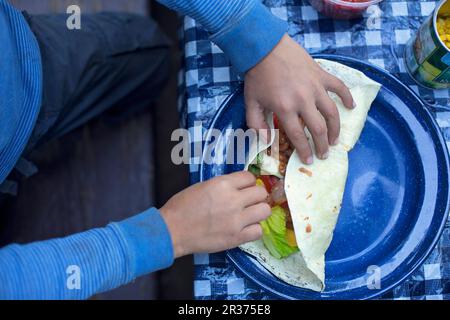A child's hands rolling a filled burrito Stock Photo