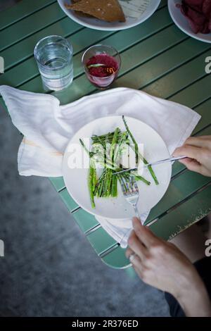 Woman eating blanched green asparagus (overhead view) Stock Photo