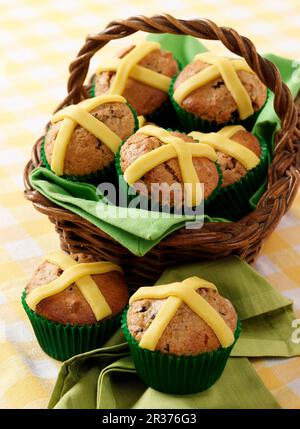 Several Easter muffins with marzipan crosses in a basket and on a napkin sitting on a gingham cloth Stock Photo