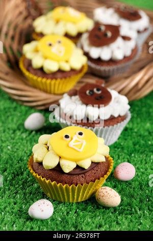 Easter animal themed cupcakes on grass and in a basket with mini easter eggs Stock Photo
