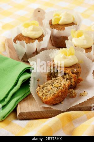 Several Seeded Lemon drizzle cupcakes in white paper cupcake cases on a wooden board Stock Photo