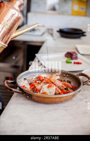 Prawns, squid and cherry tomatoes with oil in a copper pan Stock Photo