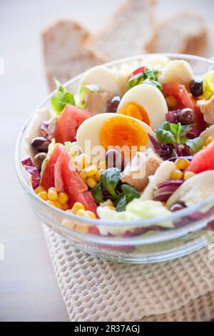 Salad bowl with tomatoes, corn, tuna, boiled egg, olives, mozzarella, radicchio and lambs lettuce Stock Photo