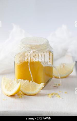 Lemon Curd in a glass jar with sliced lemons Stock Photo