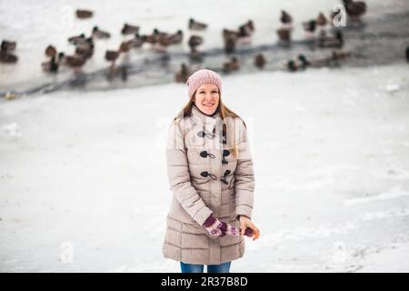 Girl feeding ducks in winter Stock Photo