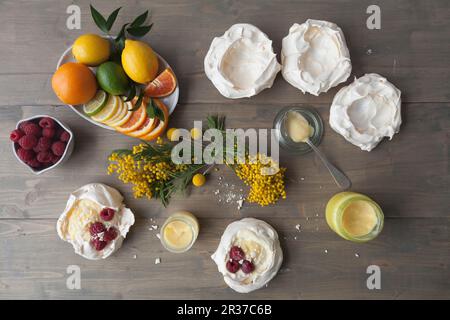 Meringue nests with lemon curd, citrus fruits and raspberries Stock Photo