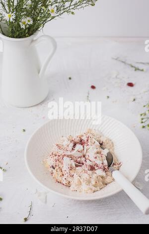 Overnight oats or bircher muesli with coconut and cranberries, and fresh daisies Stock Photo
