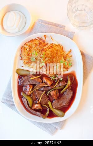 Beef stroganoff with potato rosti, gherkins and mushrooms in red wine sauce Stock Photo