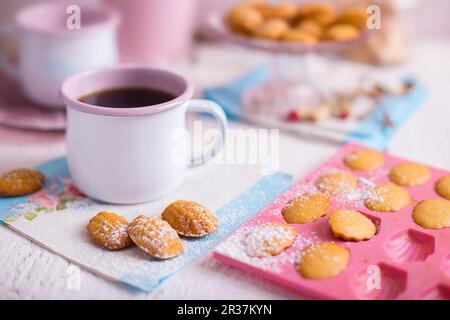French Madeleines on a white wooden table with blue and pink decorations and a cup of coffee Stock Photo