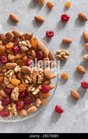 Nuts and dried fruits on the plate on the concrete surface Stock Photo