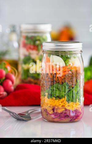 Layered salad in glass jars with spinach, carrots and cheese Stock Photo