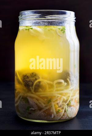 Chicken soup with liver dumplings and egg noodles in a glass jar Stock Photo