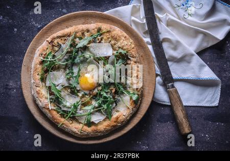 Pizza with fried egg, rocket and parmesan (top view) Stock Photo