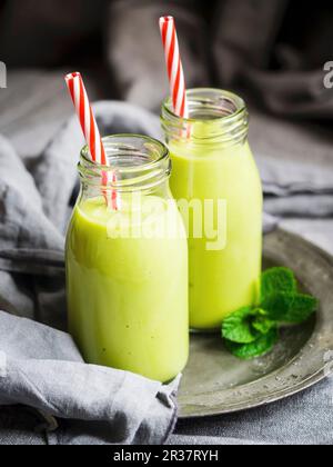 Vegan green smoothies in glass bottles with straws Stock Photo