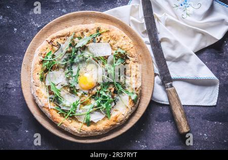 A pizza with rocket, fried egg and parmesan (seen from above) Stock Photo