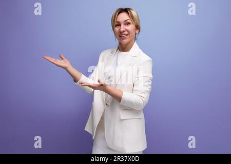 young blond woman dressed in a jacket and dress demonstrates with her hands an advertising offer Stock Photo