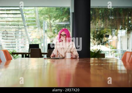 Serious young female entrepreneur drinking coffee when reading news article on tablet computer Stock Photo
