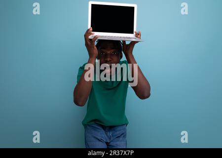american young brunette man in casual t-shirt shows laptop screen with mockup for web page Stock Photo