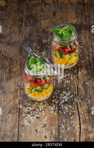 Rice salad in a glass jar with wild rice, sweetcorn, cucumber, tomato and lamb's lettuce Stock Photo